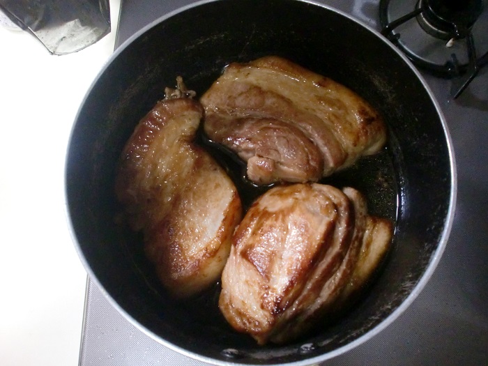 鍋で豚肉を調味料で煮込む